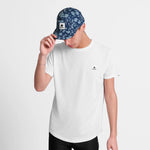 Person wearing a white t-shirt and a blue floral cap on a light gray background