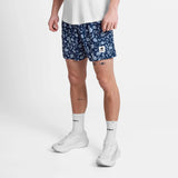 Person wearing navy floral shorts on a white background