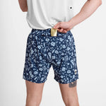 Person wearing navy floral shorts on a white background