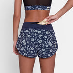 Person wearing navy floral shorts on a plain background