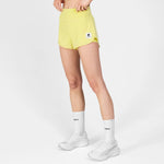 Person wearing yellow athletic shorts with a logo on a white background