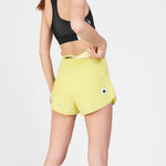 Person wearing yellow athletic shorts with a logo on a light gray background
