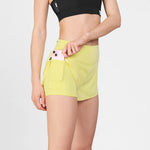 Person wearing yellow athletic shorts with a pink phone in the pocket on a light gray background