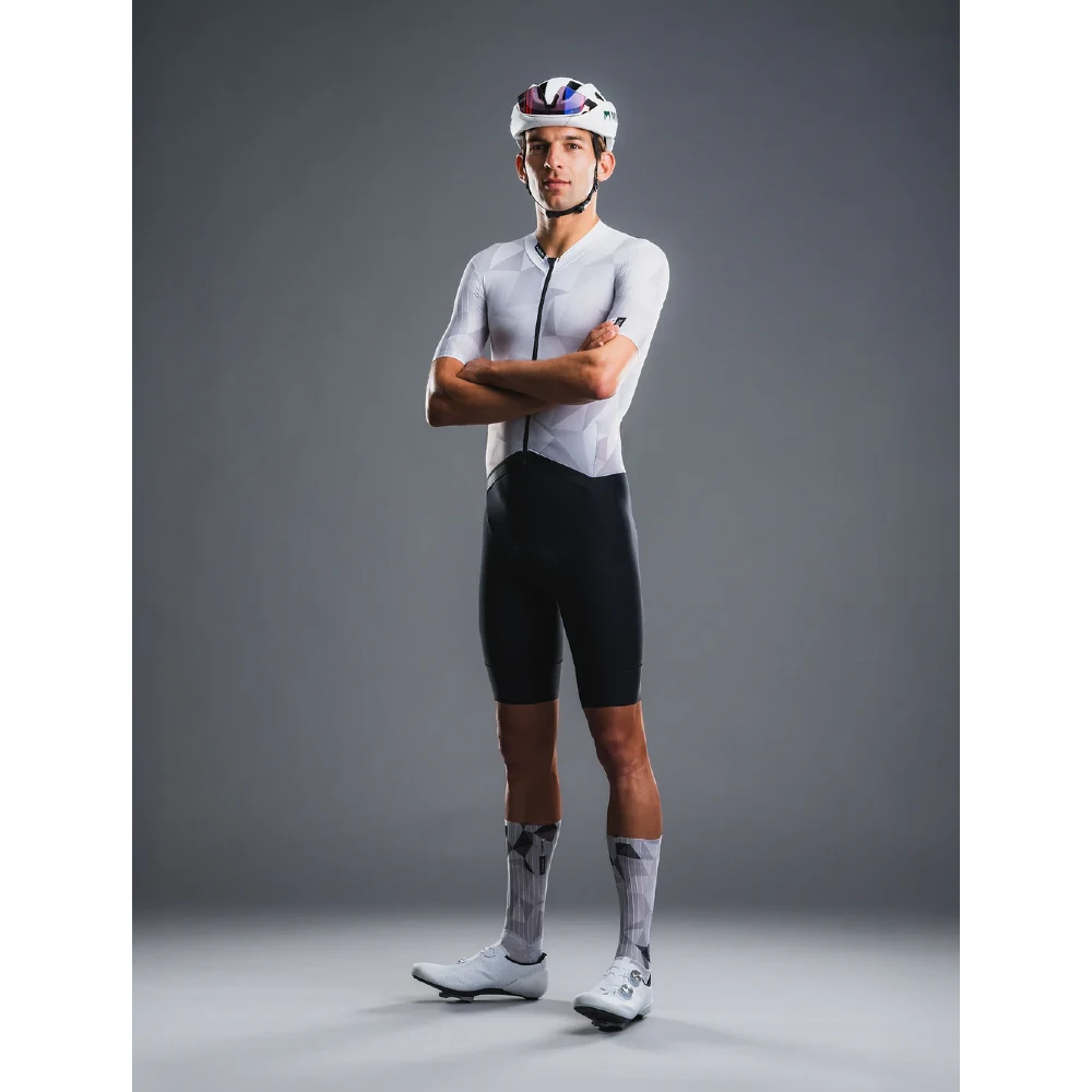 Cyclist wearing a white jersey and black shorts with a helmet on a gray background