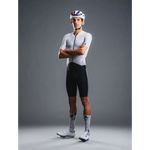 Cyclist wearing a white jersey and black shorts with a helmet on a gray background