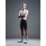 Cyclist wearing a white jersey and black shorts with a helmet on a gray background