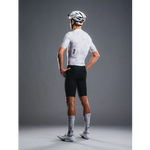 Person wearing a white cycling jersey and black shorts with a helmet on a gray background