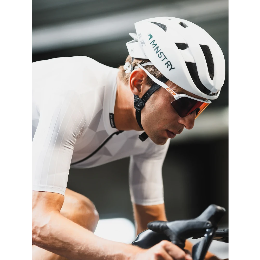 Cyclist wearing a white helmet with 'Ministry' branding on a blurred background
