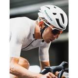 Cyclist wearing a white helmet with 'Ministry' branding on a blurred background