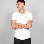Person wearing a white t-shirt with a small logo on a gray background
