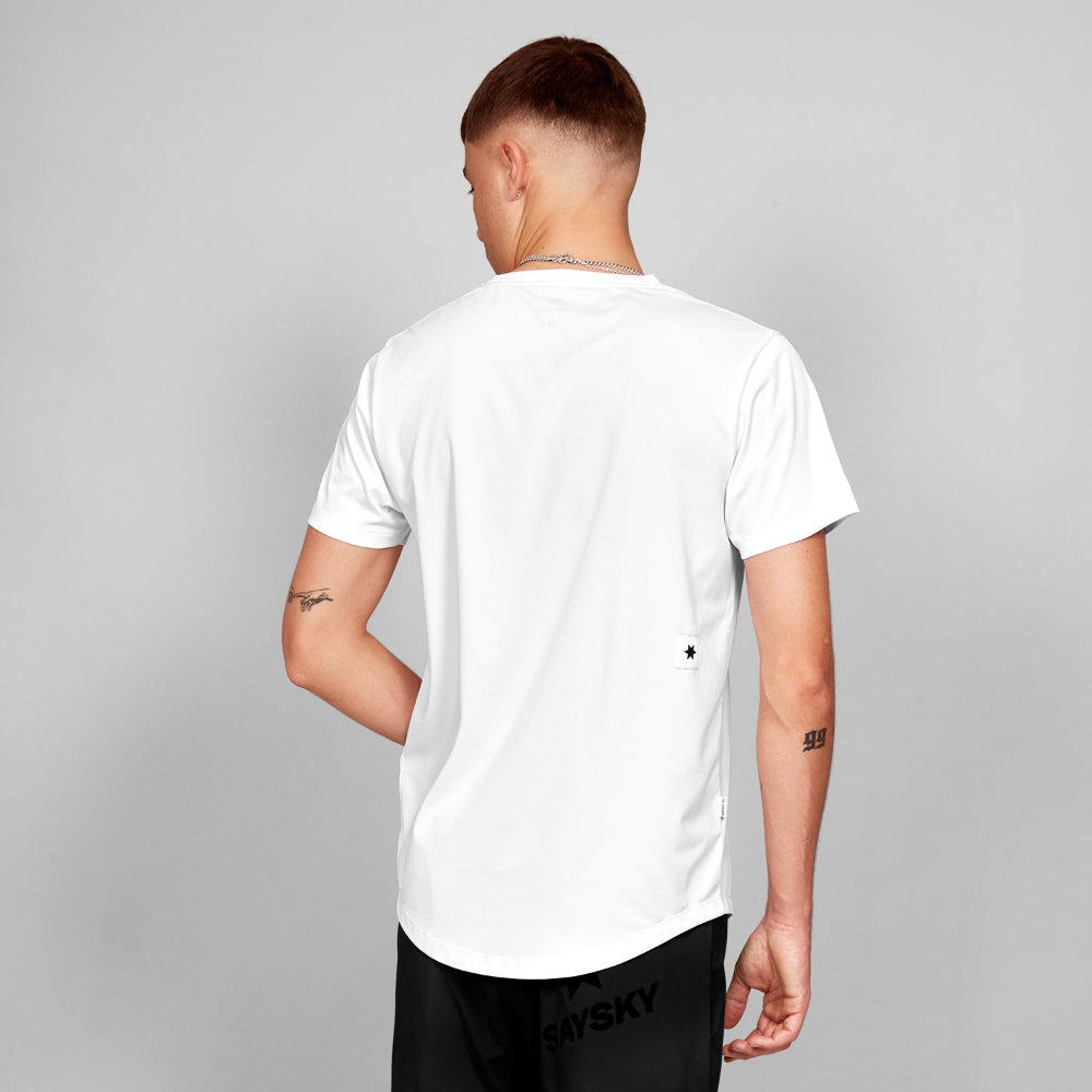 Person wearing a white t-shirt with a visible brand logo on a gray background