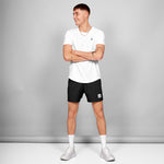 Man wearing a white t-shirt and black shorts with a logo on a gray background