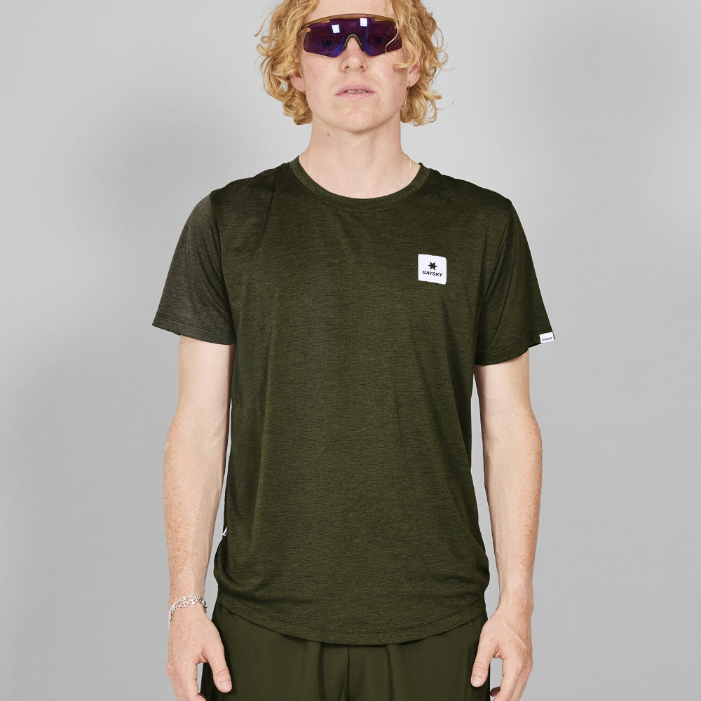Person wearing a green t-shirt with a logo on a gray background