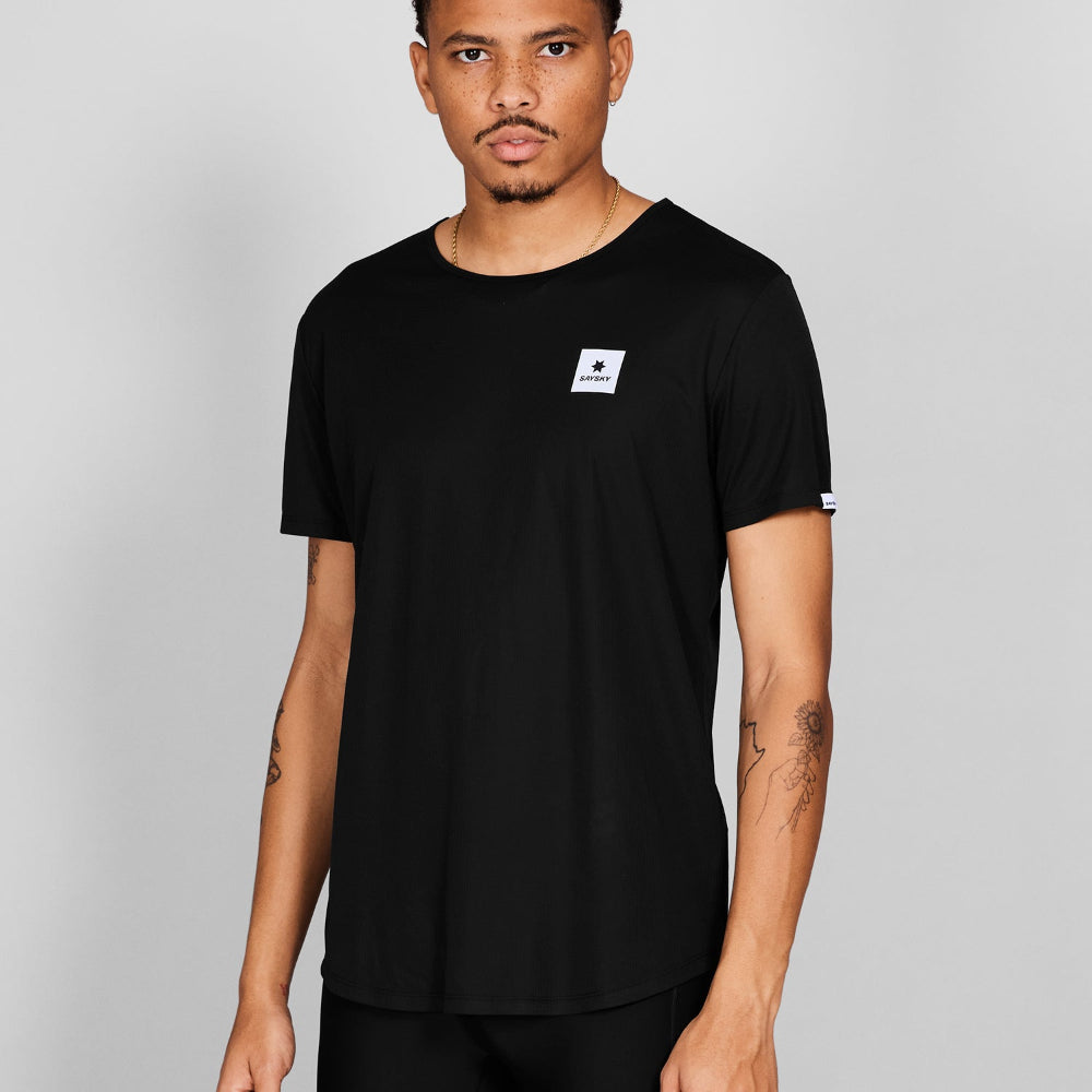 Man wearing a black t-shirt with a small logo on a gray background