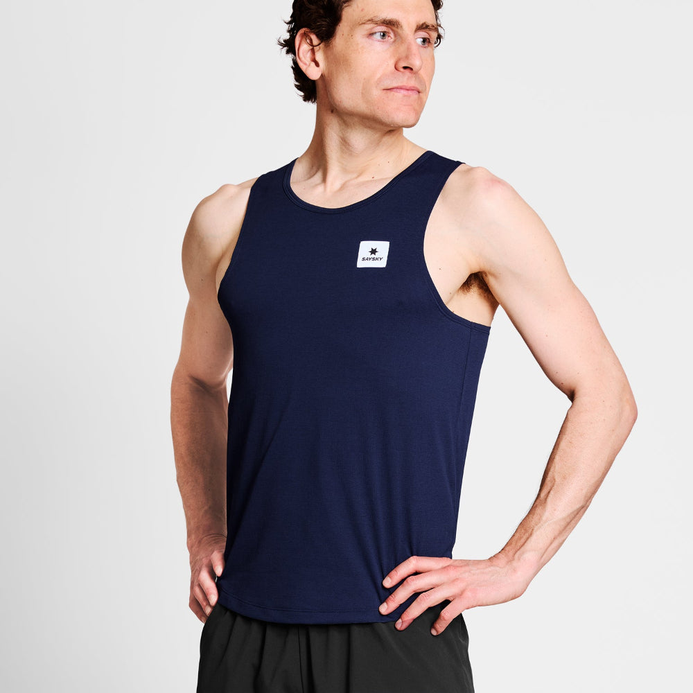 Man wearing a navy tank top with a logo on a light gray background