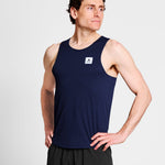 Man wearing a navy tank top with a logo on a light gray background