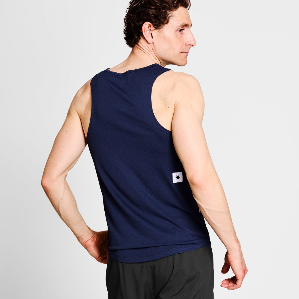 Man wearing a navy tank top with a small logo on a light gray background