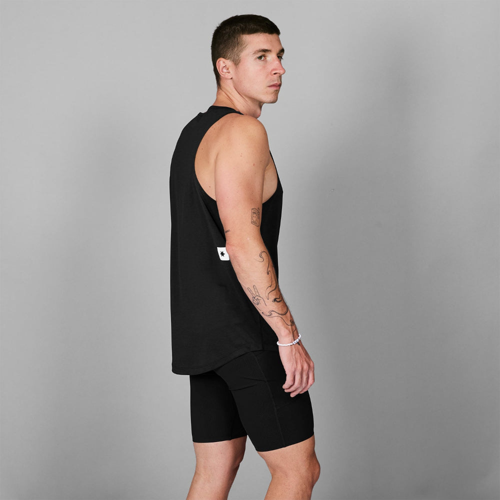Man wearing a black sleeveless top and shorts on a gray background