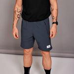 Person wearing navy shorts with a brand logo on a neutral background