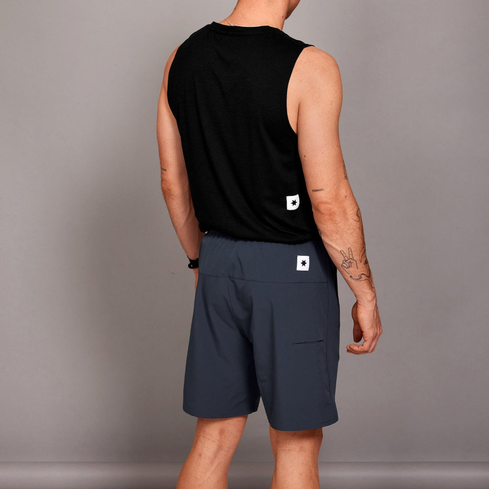 Person wearing a black sleeveless shirt and dark shorts on a gray background