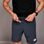Person wearing navy shorts with a brand logo on a gray background