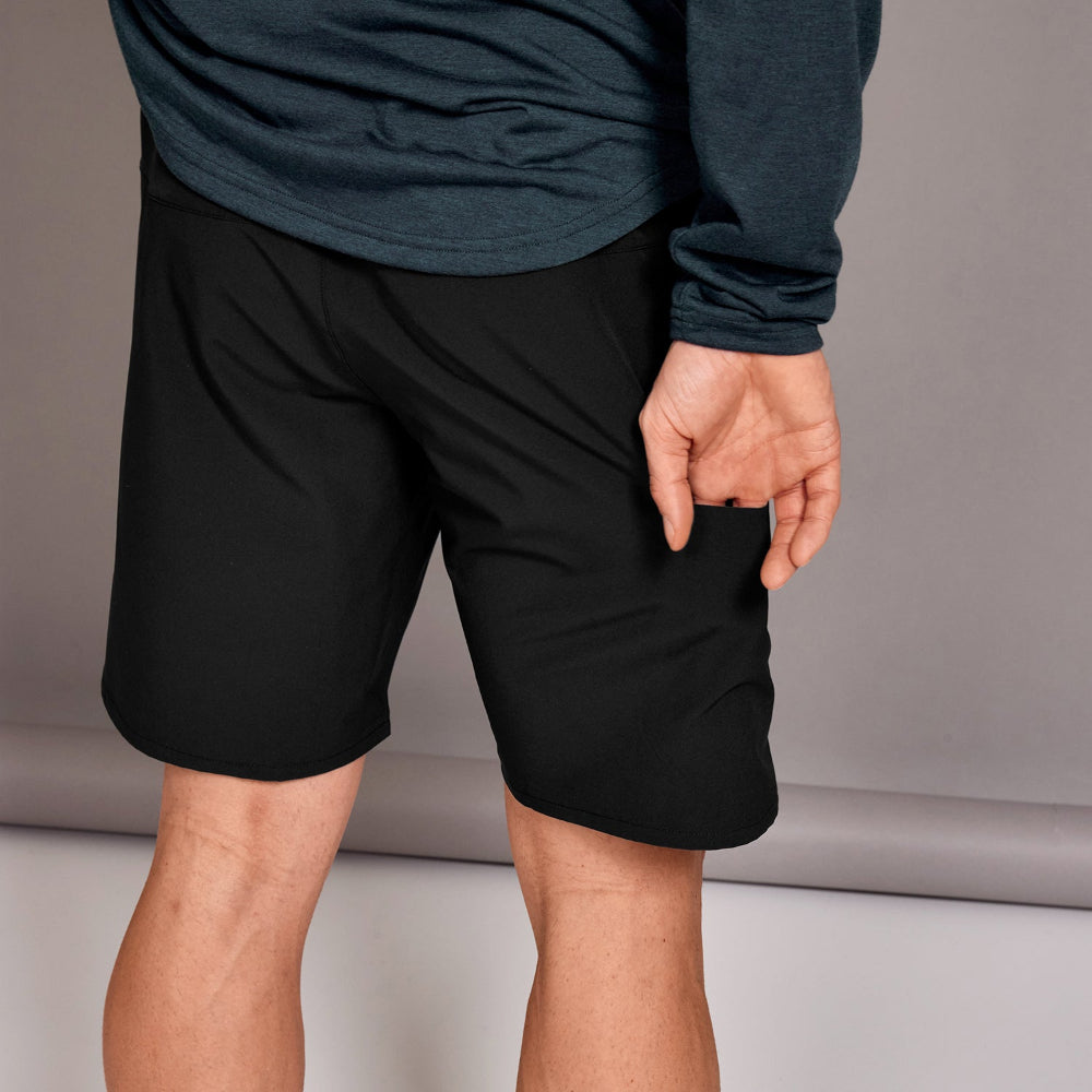 Person wearing black shorts and a dark long-sleeve shirt on a neutral background