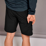 Person wearing black shorts and a dark long-sleeve shirt on a neutral background