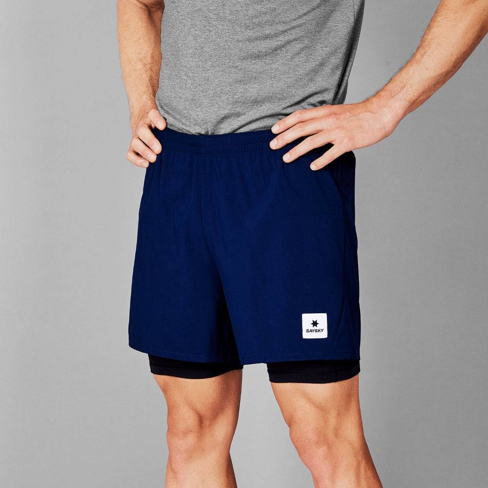 Person wearing navy shorts with a brand logo on a gray background