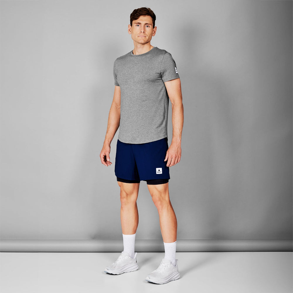 Man wearing a gray t-shirt and navy shorts against a gray background