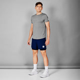Man wearing a gray t-shirt and navy shorts against a gray background