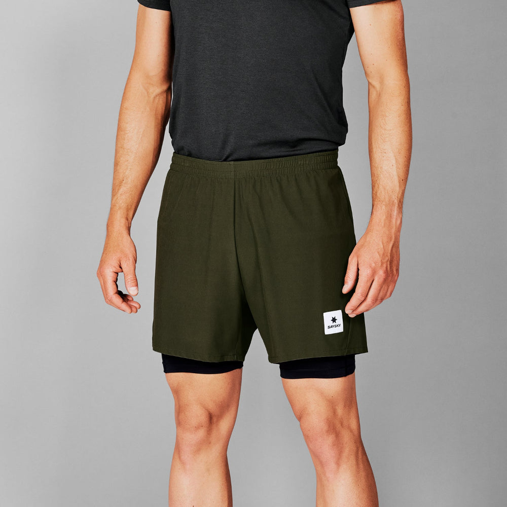 Person wearing green athletic shorts with a small logo on a gray background