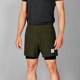 Person wearing green athletic shorts with a small logo on a gray background