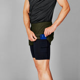 Person wearing black shorts with a blue device in the pocket against a gray background