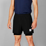 Person wearing black shorts with a small white logo on a gray background
