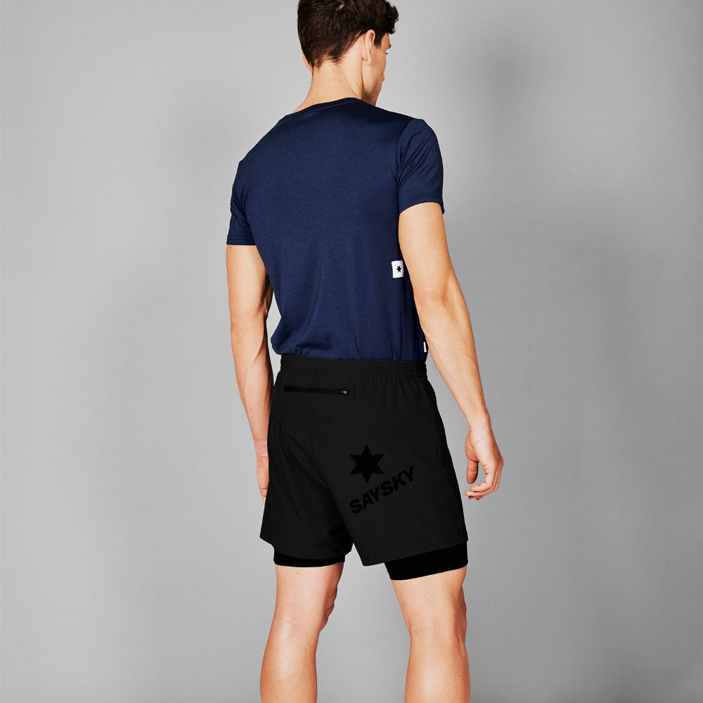 Person wearing navy blue t-shirt and black shorts with a brand logo on a gray background
