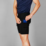 Person wearing black shorts with a blue device in the pocket against a gray background
