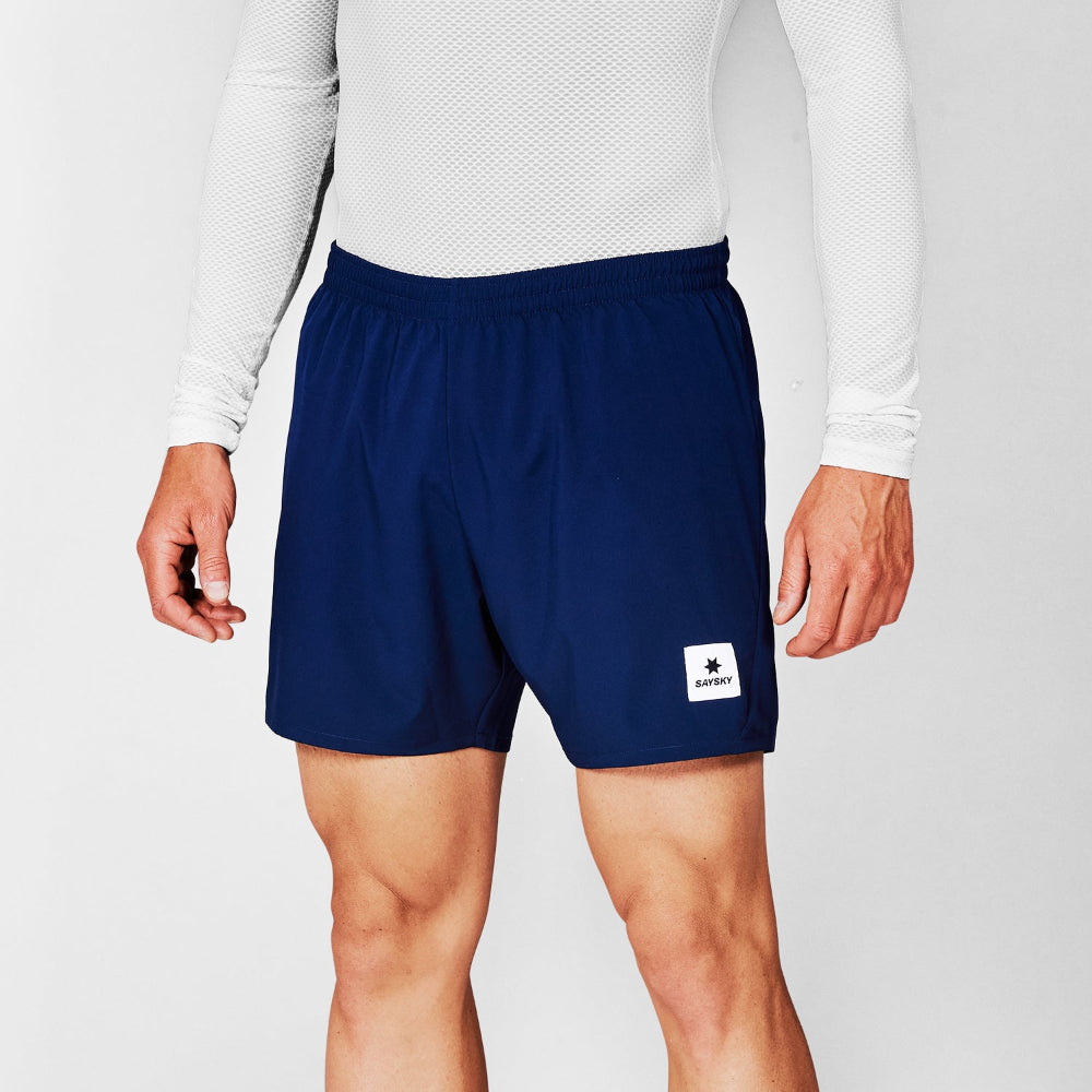 Person wearing navy shorts with a brand logo on a light gray background