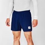 Person wearing navy shorts with a brand logo on a light gray background