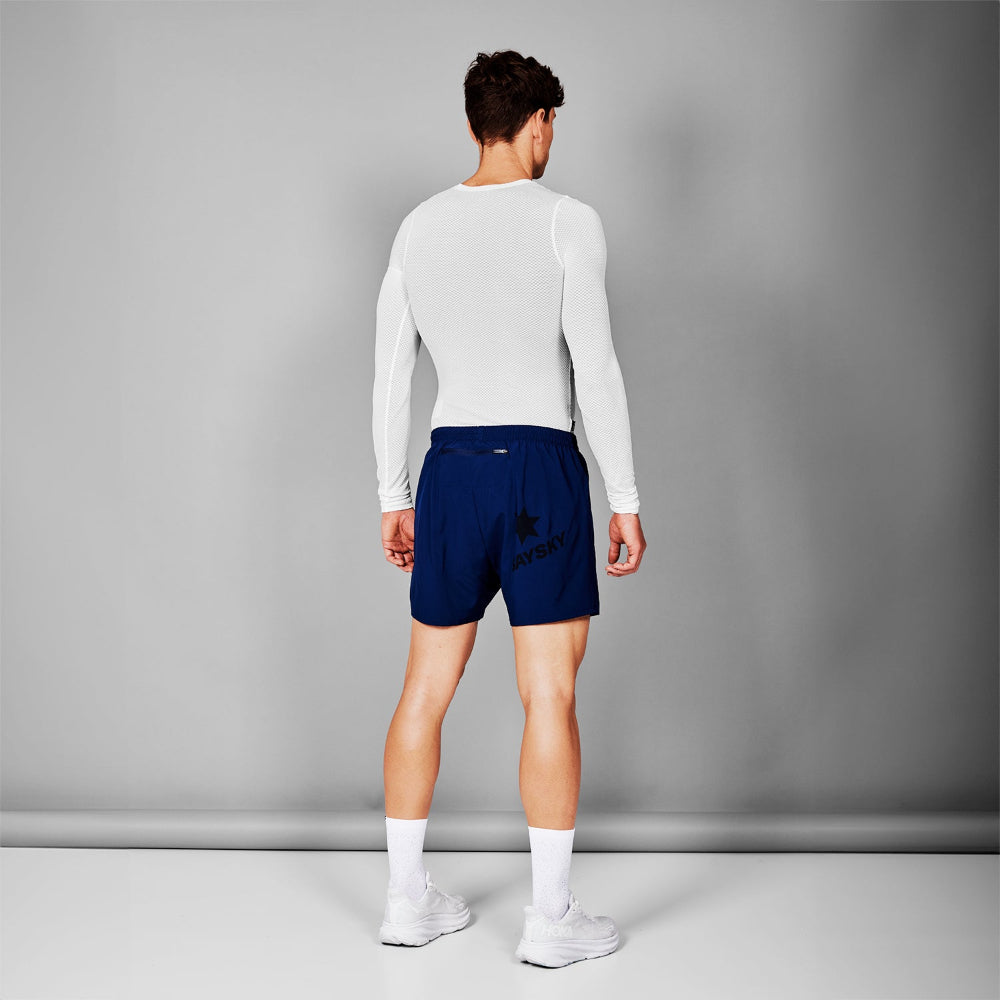 Person wearing a white long-sleeve shirt and blue shorts on a gray background