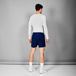 Person wearing a white long-sleeve shirt and blue shorts on a gray background