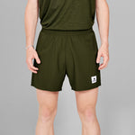 Person wearing green athletic shorts with a small logo on a gray background