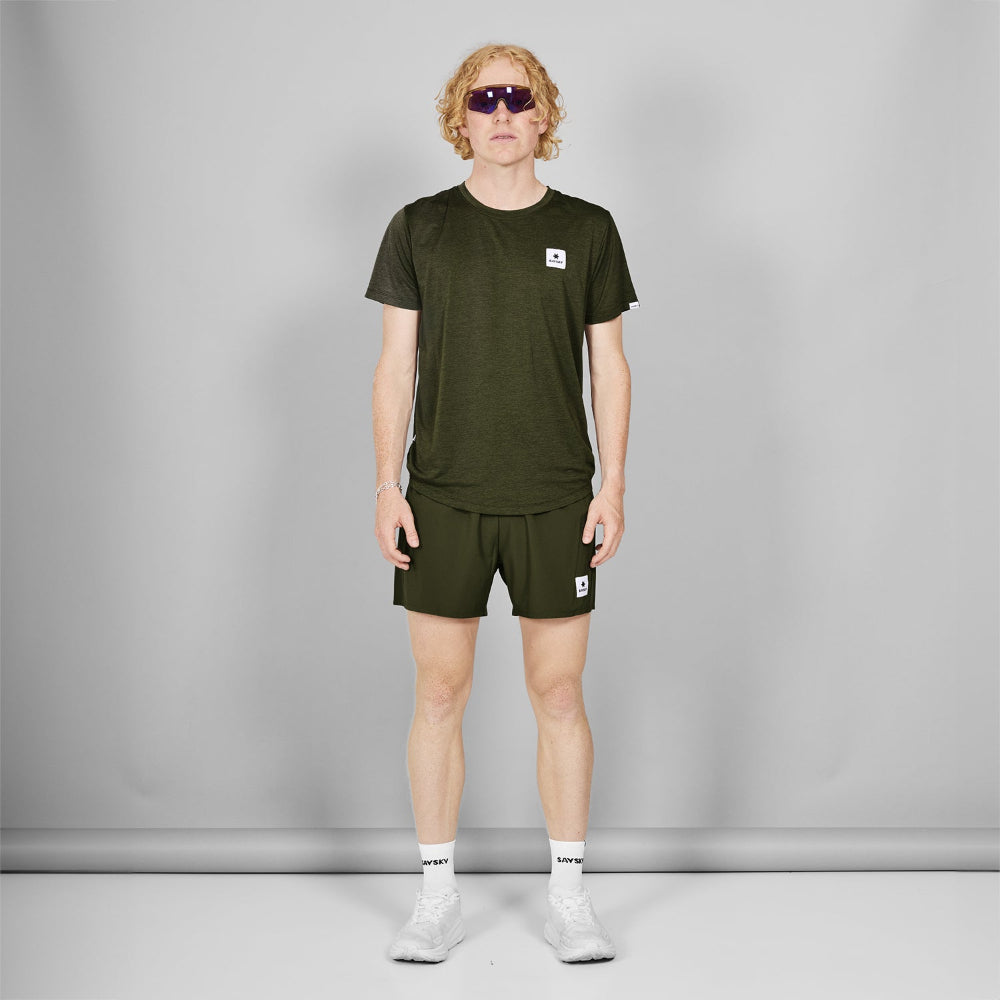 Person wearing a green t-shirt and shorts set with a small logo, standing against a plain background.