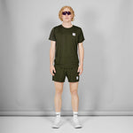 Person wearing a green t-shirt and shorts set with a small logo, standing against a plain background.