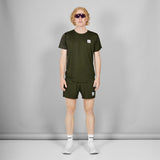 Person wearing a green t-shirt and shorts set with a small logo, standing against a plain background.