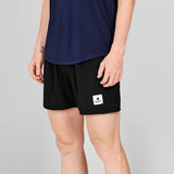 Person wearing black shorts with a logo on a gray background