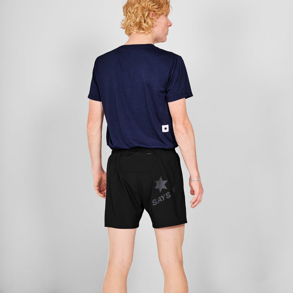 Person wearing a navy blue t-shirt and black shorts with 'SAYS' branding on a gray background