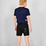 Person wearing a navy blue t-shirt and black shorts with 'SAYS' branding on a gray background
