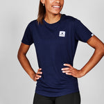 Person wearing a navy blue t-shirt with a logo on a gray background