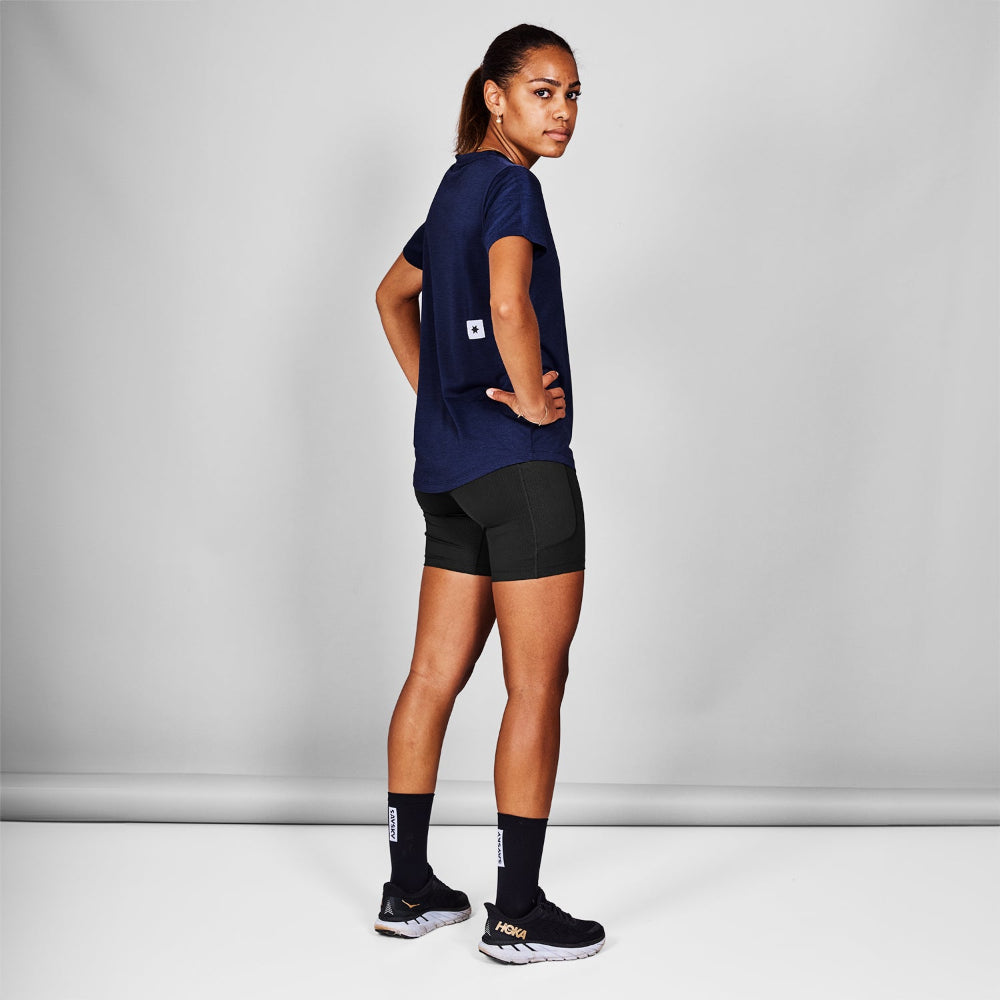 Person wearing a navy blue athletic outfit with black shorts and socks on a gray background