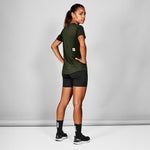 Person wearing a green athletic shirt and black shorts on a gray background